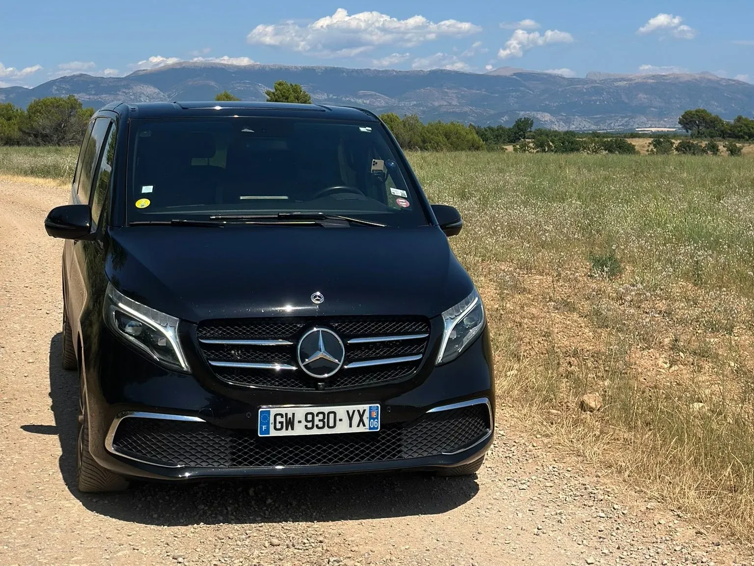 Black Massilia Services VTC Mercedes V-Class van on a Provence country road, mountains in the background