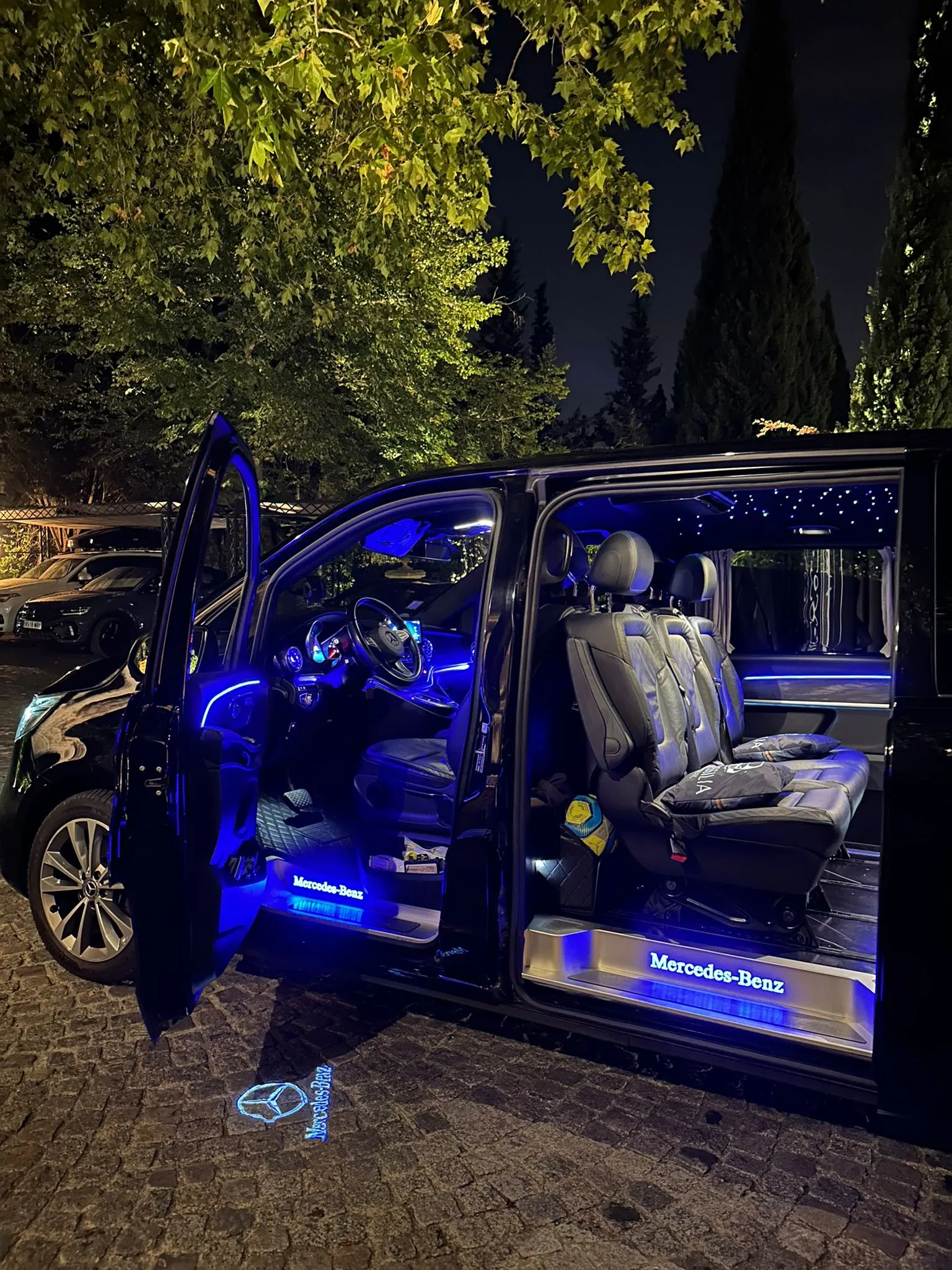 Mercedes V-Class van at night, doors open, blue ambient lighting and leather seats