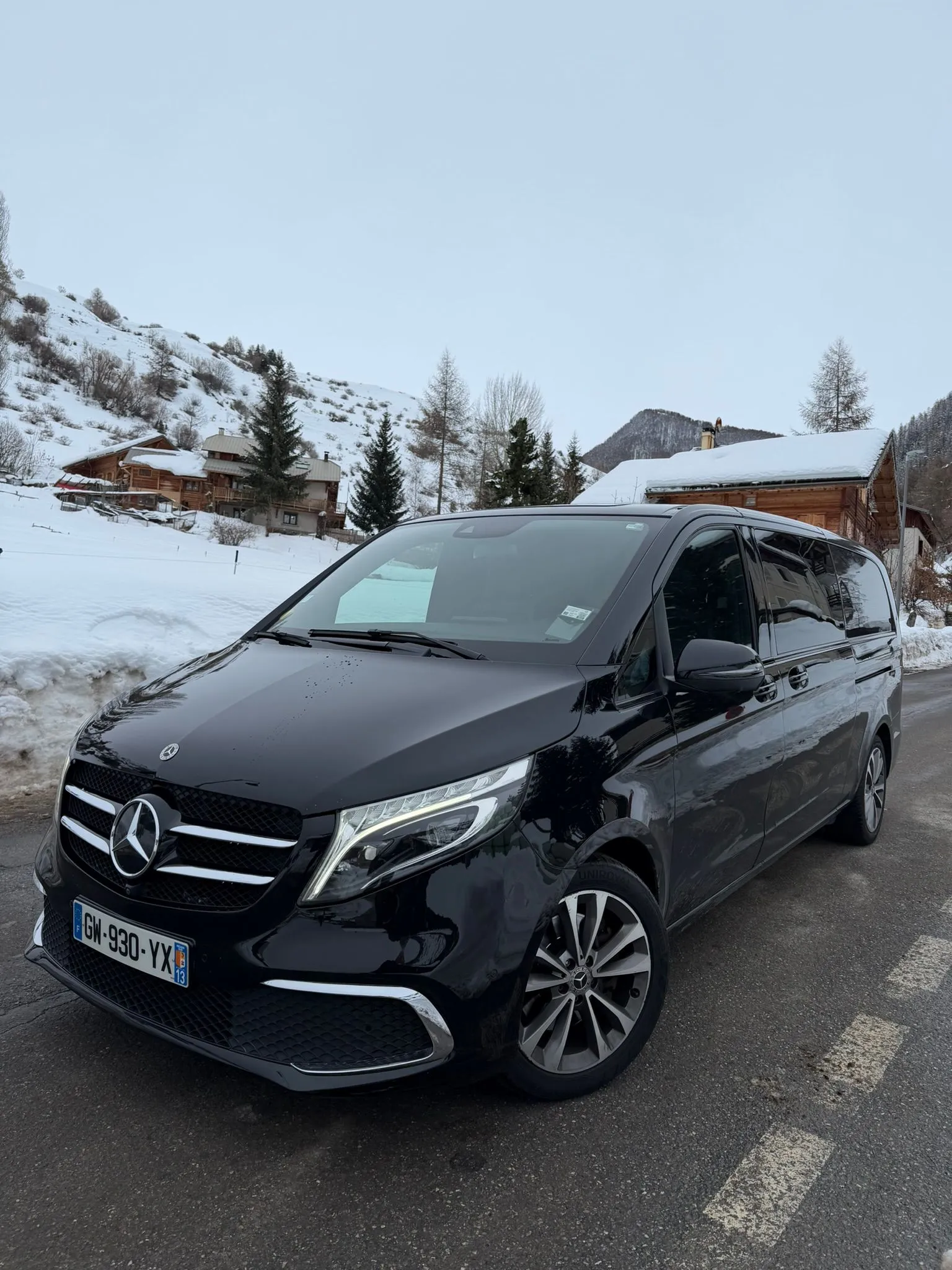 Black Massilia Services VTC Mercedes V-Class van in the snowy mountains, in front of chalets